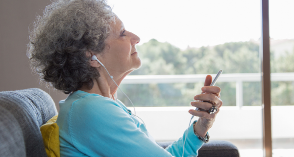 Senior woman listening to music through her ear buds connected to her phone.