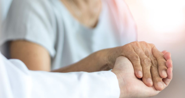 Caregiver holding the hand of a senior.