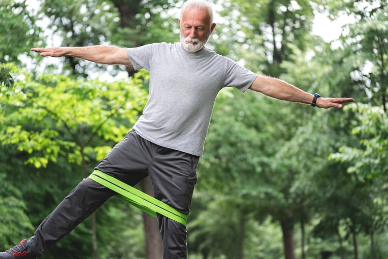 Senior man doing side leg raise exercise to strengthen hips