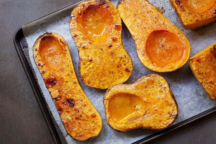 Tray with roasted butternut squash and parchment paper.