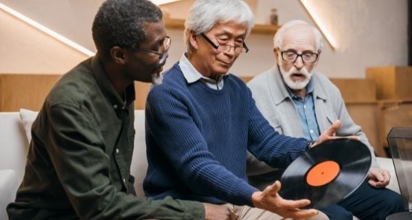 Three senior men in a hobby group looking at a record.