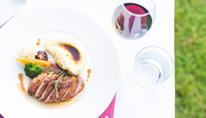 A seared duck breast and a glass of red wine. 