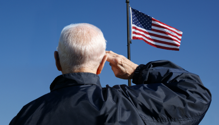 Senior American veteran saluting the American flag.
