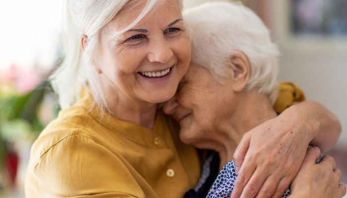 Adult child hugging her mother who has Alzheimer’s.