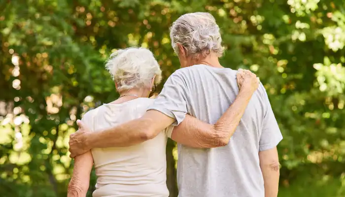 Mature man and woman walking with their arms around eachother