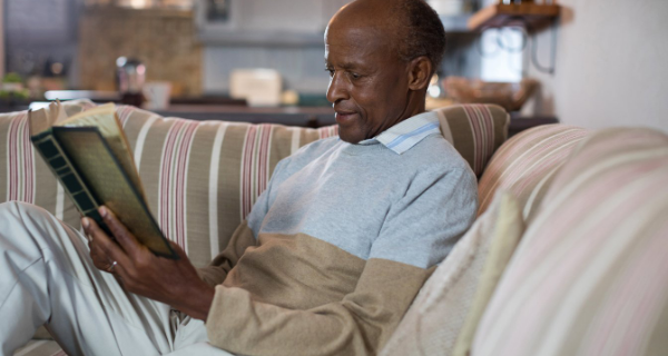 Senior man sitting on sofa reading a book.
