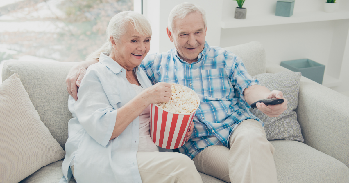 Senior couple watching a movie together while eating popcorn.