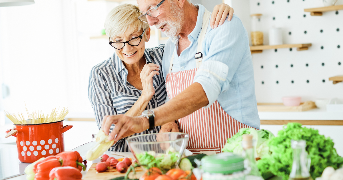 A senior couple in a modern kitchen prepare a Mediterranean diet recipe for dinner at home.