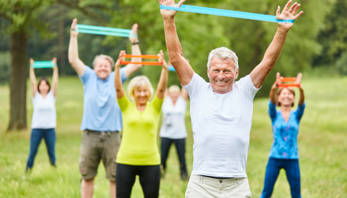 Mature adults exercising in a group with stretch bands in a physiotherapy program to stay fit. 